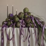 Artichoke centerpiece with purple ribbons and tall black candles