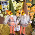 Two fall gnome figurines with faux flowers and plaid outfits