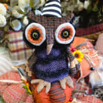 Fabric owl figurine surrounded by autumn pumpkins and flowers