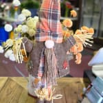 Scarecrow decoration with small pom-pom flowers in a vase