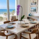Purple orchid arrangement in a white pot on a dining table by the ocean