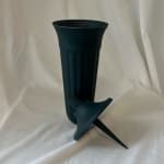 Dark teal plastic vase with a separate funnel insert on white fabric