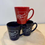 Three Arkansas-themed coffee mugs stacked on a round surface