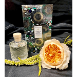 Perfume bottle, floral candle box, and a peach rose on dark fabric