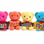 Four plush teddy bears holding candy bars on a white background