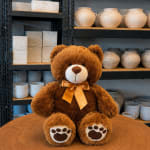 Brown teddy bear with a satin bow sitting on a wooden table