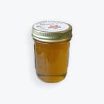 Jar of honey with a metal lid on a white background