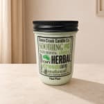 A jar candle with a black lid labeled Thai Pear.