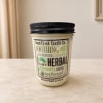 Jar candle with a black lid labeled White Peach & Clove