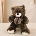 Brown plush teddy bear with a checkered bow sitting on a table