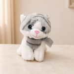Plush gray-and-white cat toy with a ribbon bow sitting on a table