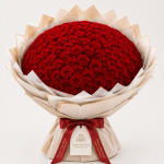 Large bouquet of red roses wrapped in beige paper with a red ribbon