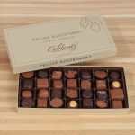 Open box of assorted chocolates on a wooden surface