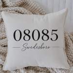 White decorative pillow with black text on a knitted throw