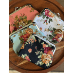 Three floral fabric coin purses with metal clasps on a wooden tray