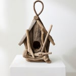 Rustic wooden birdhouse made from driftwood on a white pedestal