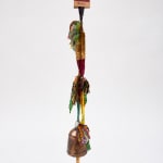 Hanging decorative tassel with colorful fabric strips and a copper bell