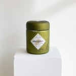 Green candle jar labeled Grapefruit Pine on a white pedestal