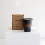 Black candle in a cup with a cardboard box beside it