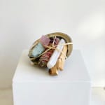 Bundle of crystals and dried botanicals tied with raffia on a white pedestal
