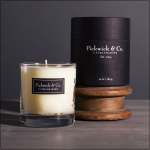 Glass candle in a clear tumbler with a black branded box behind it
