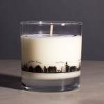 White candle in a clear glass tumbler with a city skyline design