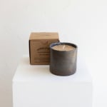 Scented candle in a dark container with a cardboard box