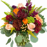 Mixed bouquet of roses, chrysanthemums, and orchids in a glass vase