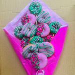 Box of decorated donuts on pink tissue paper