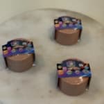 Three small candles in round containers with colorful labels