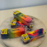 Four packaged rainbow butter sticks on a round tray