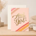 Pink greeting card reading "Atta Girl" with envelope behind it