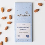 Box of dark chocolate almond candy with almonds scattered around it