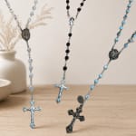 Rosary necklaces with beaded chains and metal crosses on a tabletop