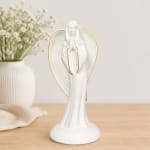 White angel figurine on a tabletop with a vase of baby's breath