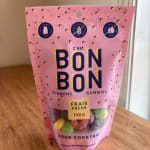 Pink bag of sour cocktail gummies standing on a wooden table