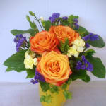 Orange roses with purple filler flowers in a yellow vase