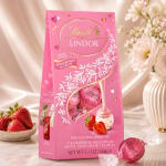 Pink Lindt Lindor strawberry cream chocolate box with strawberries and flowers nearby
