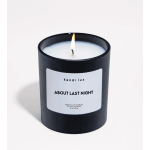 Lit scented candle in a black glass jar with a white label