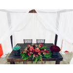 Three floral arrangements on a table, including red roses and turquoise roses in black containers