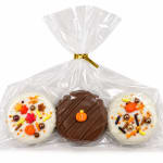 Three decorated chocolate-covered treats in a clear gift bag