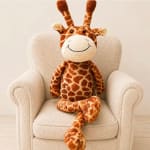 Plush giraffe toy sitting on a beige armchair