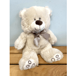 Plush teddy bear with a satin ribbon sitting on a wooden surface