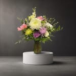 Mixed bouquet of pastel flowers in a glass vase on a pedestal