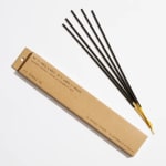 Box of charcoal incense sticks beside several loose sticks
