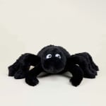 Black plush spider toy with large eyes on a plain background