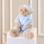 Teddy bear in blue striped pajamas sitting on a white box
