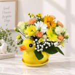Yellow duck-shaped vase filled with mixed flowers