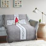 Gray quilted throw blanket with a cardinal and cross design on a sofa