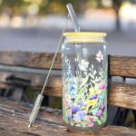 Glass jar with floral print and a straw lid on a bench
